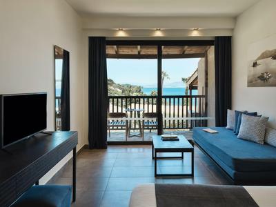 Modernes Wohnzimmer mit Sofa, Fernseher und Blick auf Terrasse und Meer.