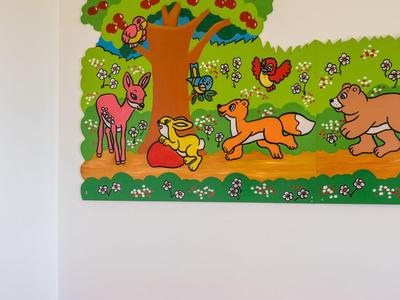 Bunte Kinderspielecke mit Ballbecken und wandgemaltem Baum und Tieren.