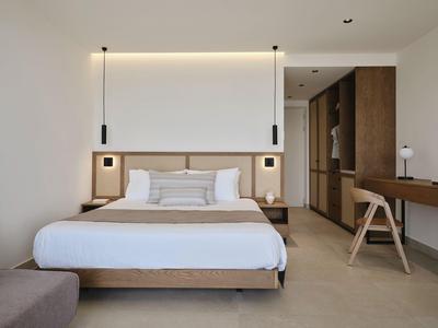 Modernes Hotelzimmer mit großem Bett, Nachttischen und Schreibtisch in neutralen Tönen.