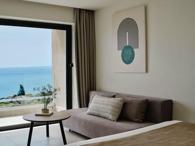 Modern eingerichtetes Hotelzimmer mit Meerblick, Sofa, Bett und minimalistischer Dekoration.