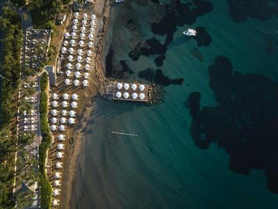 Luftaufnahme eines Hotels an der Küste mit Bungalows, Strand und klarem Meerwasser.