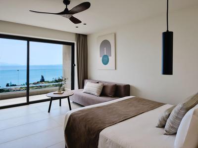 Modernes Hotelzimmer mit Bett, Sofa, großem Fenster und Meerblick.
