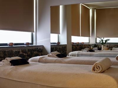 Ein moderner Spa-Raum mit mehreren Massageliegen, Handtüchern und gedämpftem Licht.