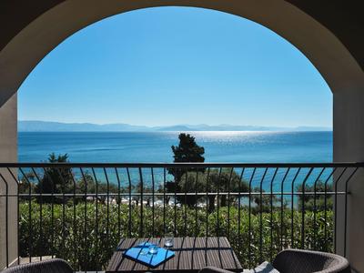 Blick durch einen Bogen auf einen Balkon mit Blick auf das Meer und einen blauen Himmel.