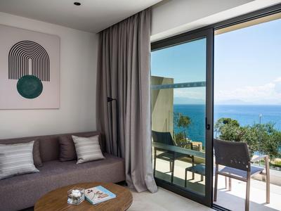 Moderner Hotelzimmerbereich mit Sofa, Kunstwerk und Balkon mit Meerblick.