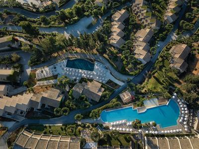 Luftaufnahme einer Wohnanlage mit mehreren Gebäuden, großen Pools und umgeben von Grünflächen.