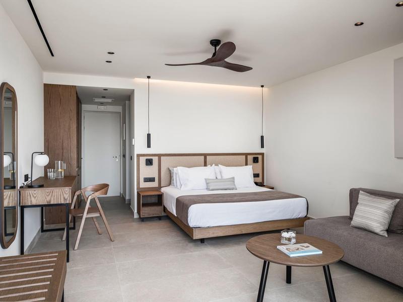 Modernes Hotelzimmer mit Doppelbett, Schreibtisch, Sofa und minimalistischem Design.