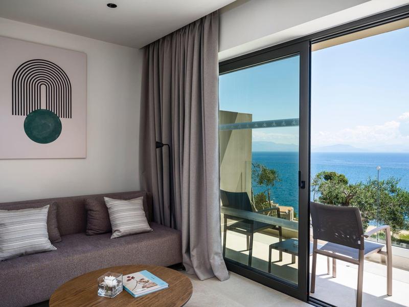Moderner Hotelzimmerbereich mit Sofa, Kunstwerk und Balkon mit Meerblick.