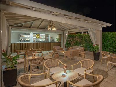 Bar extérieure confortable avec meubles en rotin et éclairage dans un cadre hôtelier ou de vacances.