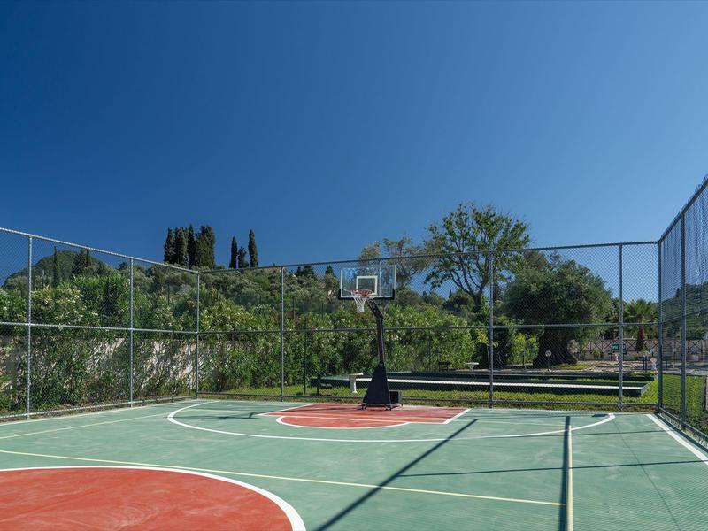 Ein leerer Basketballplatz im Freien mit grünem Boden und Körben bei klarem Himmel.