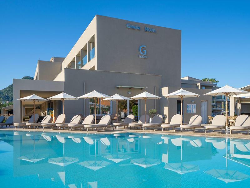 Moderner Hotelkomplex mit Außenpool und Liegestühlen bei klarem Himmel