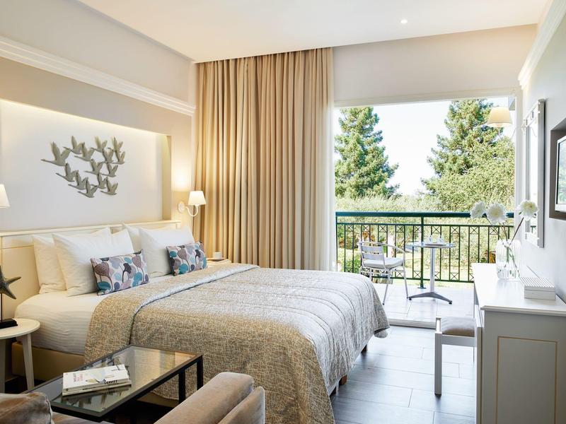 Modernes Hotelzimmer mit Doppelbett, Balkon und Blick auf Bäume