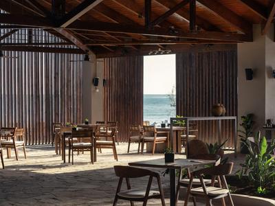 Helles Café mit Holzmöbeln und freiem Blick auf Meer durch große Holztore.