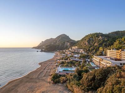 Blick auf einen Strand mit Hotels und Bergen bei Sonnenuntergang.
