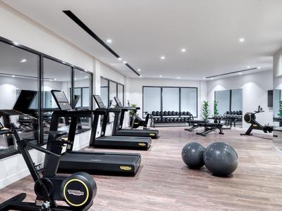 Moderner Fitnessraum in einem Hotel mit Laufbändern und Fitnessbällen auf Holzboden.