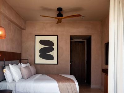 Modernes Schlafzimmer mit großem Bett, weißer Bettwäsche, abstraktem Bild und Deckenventilator.