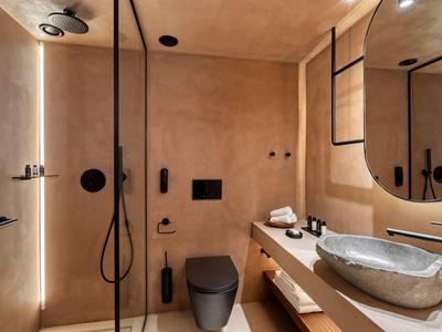 Modernes Badezimmer mit beiger Wand, schwarzer Toilette, großem Spiegel und grauer Stein-Waschschale.