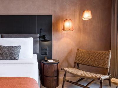 Modernes Hotelzimmer mit bequemem Bett, Nachttisch und warmem Licht.