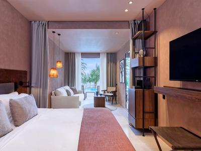 Modern gestaltetes Hotelzimmer mit Bett, Sitzbereich und TV, in warmen Farbtönen.
