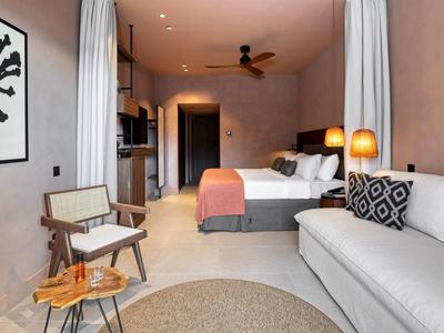 Gemütliches Hotelzimmer mit Doppelbett, Sofa, Stühlen und warmem Licht.