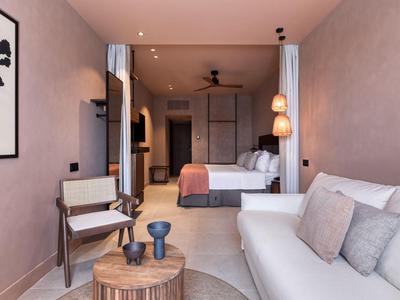 Modern eingerichtetes Hotelzimmer mit gemütlichem Sofa, Bett und Holzdetails.