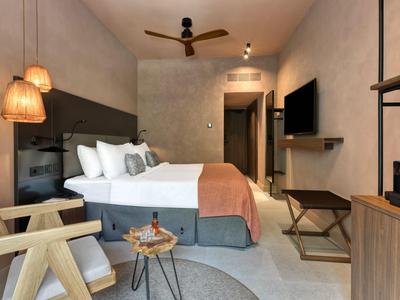 Modern eingerichtetes Hotelzimmer mit Doppelbett, Sitzbereich und warmem Licht.