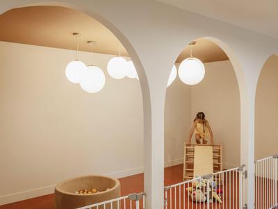 Ein heller Hotelbereich mit hohen Bögen, runder Badewanne und dekorativen Lampen.