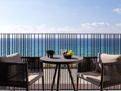 Balkon mit Tisch und Stühlen blickt auf das blaue Meer unter klarem Himmel.