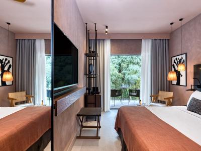 Modern eingerichtetes Hotelzimmer mit Doppelbett, Schreibtisch und Balkonblick aufs Grün.