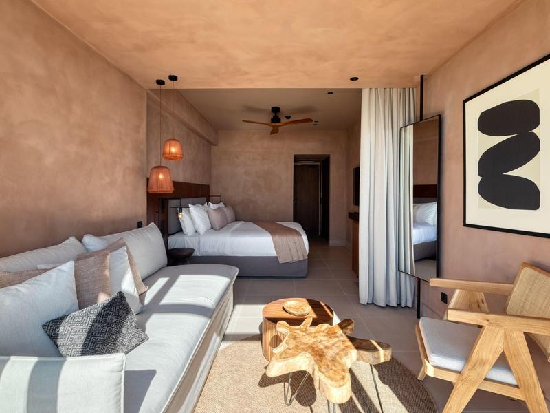 Modernes Wohnzimmer mit beiger Couch, Holztisch, Stuhl und abstraktem schwarzen Bild an Wand.