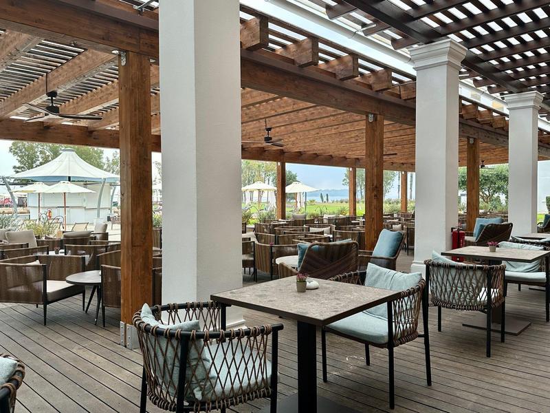 Offener, überdachter Außenbereich mit Sitzgruppen und Holzbalken in einem Hotelrestaurant.