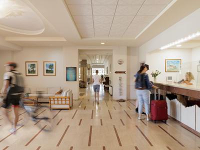 Hotelhalle mit heller Einrichtung, Sitzbereichen und Gästen mit Gepäck.