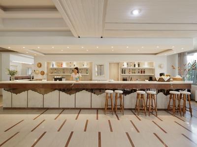 Moderner Hotelbarbereich mit Stoffhockern und hellen Holzelementen unter weißer Decke.