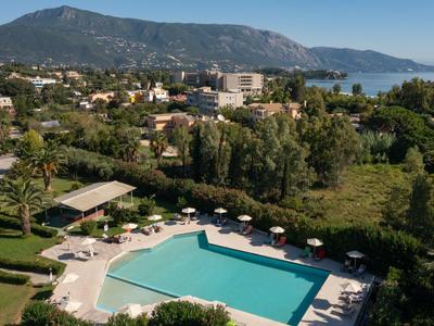 Großer rechteckiger Pool mit Liegestühlen, umgeben von Grün, dahinter Berge und Küstenblick.