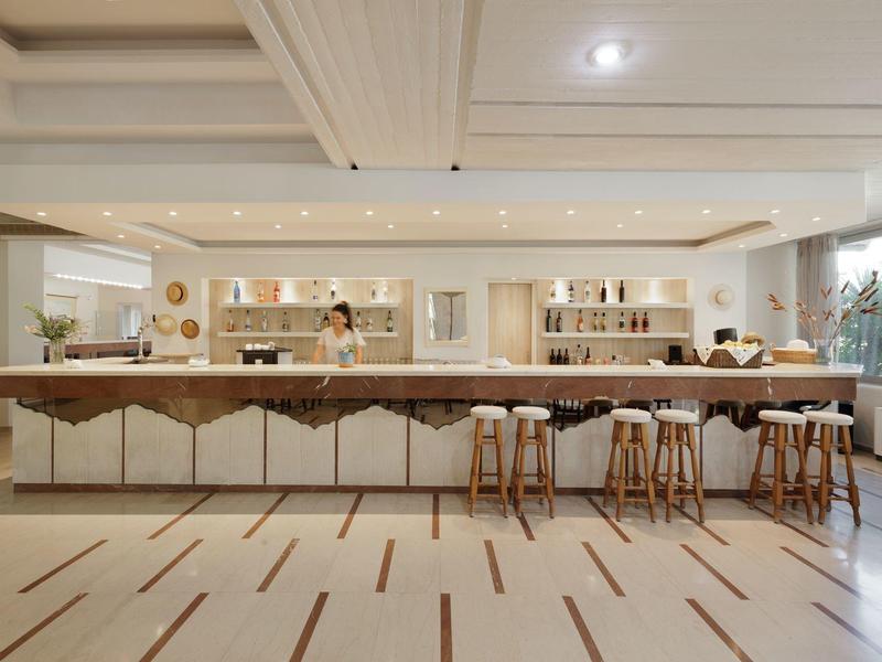 Moderner Tresen mit weißen Hockern und Holzbarhockern in hellem Raum mit großen Fenstern.