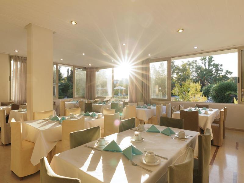 Hell beleuchteter, eleganter Speiseraum mit gedeckten Tischen und großen Fenstern, durch die Sonnenlicht fällt.