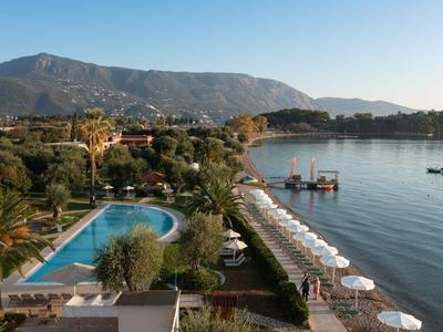 Ein Pool und Sonnenschirme am Ufer eines Sees, mit Bergen und blauem Himmel im Hintergrund.