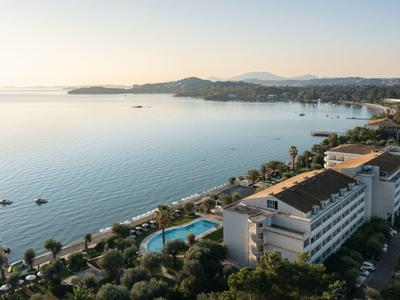 Blick auf Küstenlinie mit ruhigem Meer, Hotels, Swimmingpools und Palmen bei klarem Himmel.