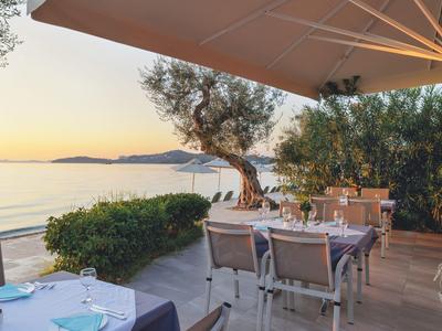 Terrace with set tables overlooking the sea at sunset.