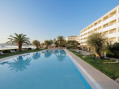 Modern hotel pool with palm trees and sea view under clear sky