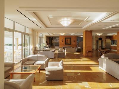 Großer, heller Raum mit Sofas, Sesseln, Holzfußboden und großen Fenstern mit Stadtblick.