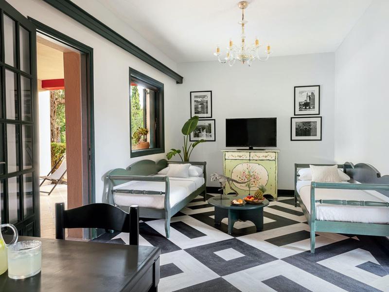 Helles Wohnzimmer mit weißen Wänden, zwei grauen Sofas, schwarzem Teppich und Flachbildfernseher.