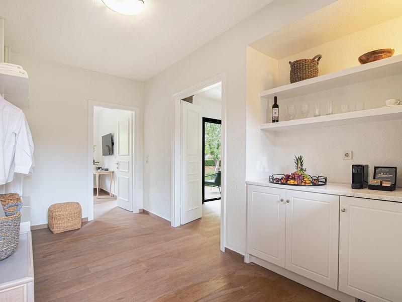 Heller Flur mit Holzboden, weißem Möbelstück mit Regalen, Körben und Haushaltsgegenständen.