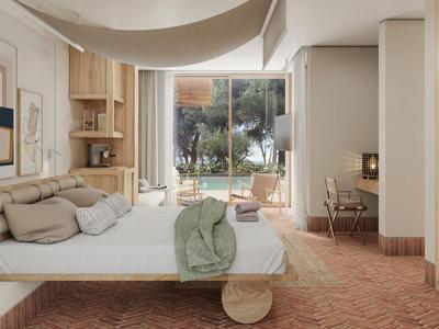 Modernes Hotelzimmer mit gemütlicher Sitzecke, großer Glasschiebetür und Blick ins Grüne.