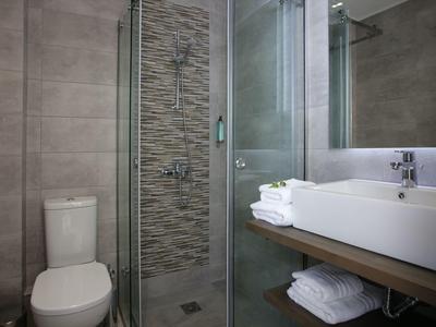 Modernes Badezimmer mit Toilette, Glasdusche, rechteckigem Waschbecken und weißen Handtüchern.