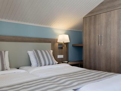 Modernes Schlafzimmer mit Doppelbett, gestreifter Bettwäsche, blauer Wand und Holzmöbeln.