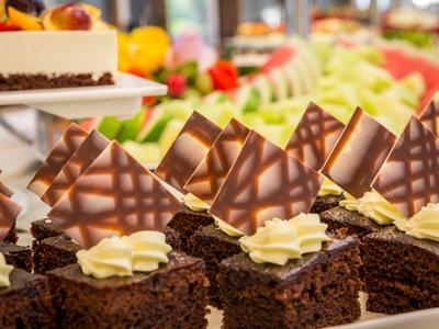 Mehrere kleine Schokoladenkuchenstücke mit Sahnetupfen und dekorativen Schokoladentafeln.