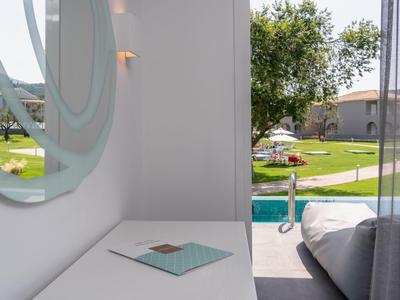 Modernes Hotelzimmer mit Poolblick, weißem Schreibtisch und rundem Spiegel an der Wand.