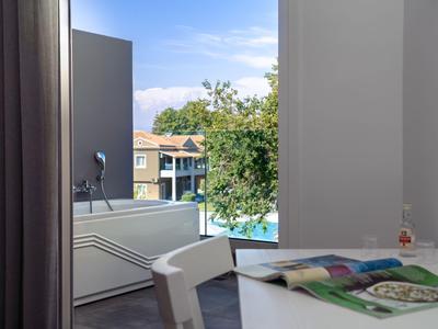 Moderner Essbereich mit Blick auf einen Balkon und Pool in einer Hotelanlage.