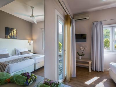 Modernes Hotelzimmer mit Doppelbett, hellem Interieur und Balkon mit Blick ins Grüne.